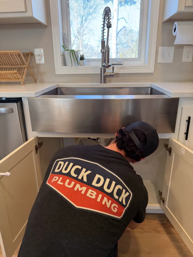 Duck Duck Plumbing working under a kitchen sink